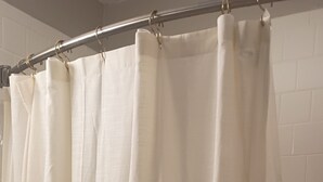 Un rideau de douche à base blanche et dont le bord inférieur est orné d’un motif.