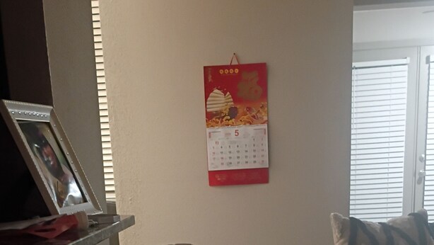 Un salon avec un canapé, un fauteuil et une table. Un calendrier est accroché au mur.