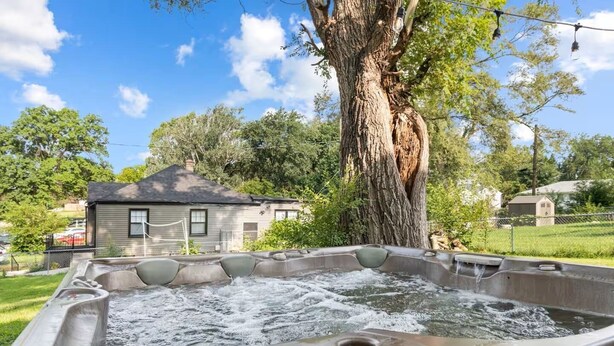 A hot tub with a tree and a house in the background.