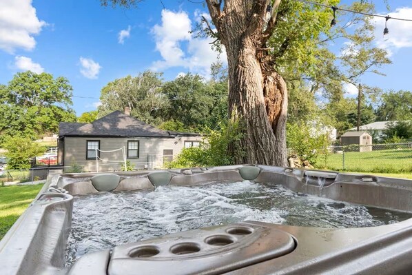 A hot tub with a tree and a house in the background.