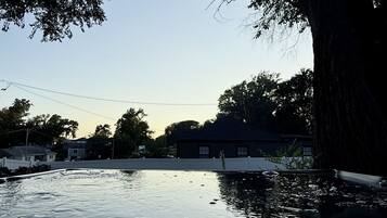 A calm body of water reflecting trees and a building.