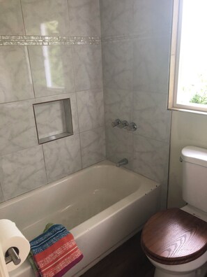 Ein Badezimmer mit Badewanne, Toilette und einem Fenster.