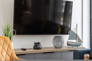 Ein modernes Wohnzimmer mit Fernseher, einer kleinen dekorativen Segelyacht und einem Blumentopf.