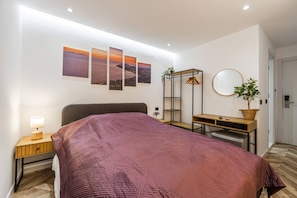 A bedroom with a bed, a desk, a chair, a lamp, a mirror, and wall art. - Konak Lemon Guesthouse Heart of Vlora (Vlorë)