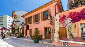 A street view with a building featuring a balcony, outdoor seating, and a small tree. - Konak Lemon Guesthouse Heart of Vlora (Vlorë)