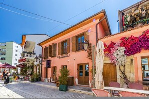 A street view with a building featuring a balcony, outdoor seating, and a small tree. - Konak Lemon Guesthouse Heart of Vlora (Vlorë)