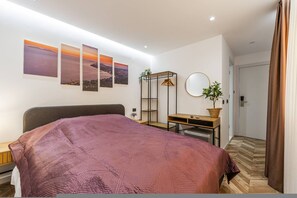 A bedroom with a bed, a desk, a chair, a potted plant, a mirror, and wall art. - Konak Lemon Guesthouse Heart of Vlora (Vlorë)
