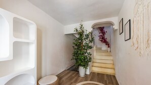 A modern interior with a staircase, a potted plant, and a wall with abstract art. - Konak Lemon Guesthouse Heart of Vlora (Vlorë)