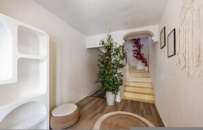 A modern interior with a staircase, a potted plant, and a wall with abstract art. - Konak Lemon Guesthouse Heart of Vlora (Vlorë)