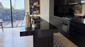 A modern kitchen with a large island, a gas stove, and a large window. - L&L Golfside Retreat (Benowa)