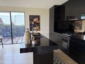 A modern kitchen with a large island, a gas stove, and a large window.