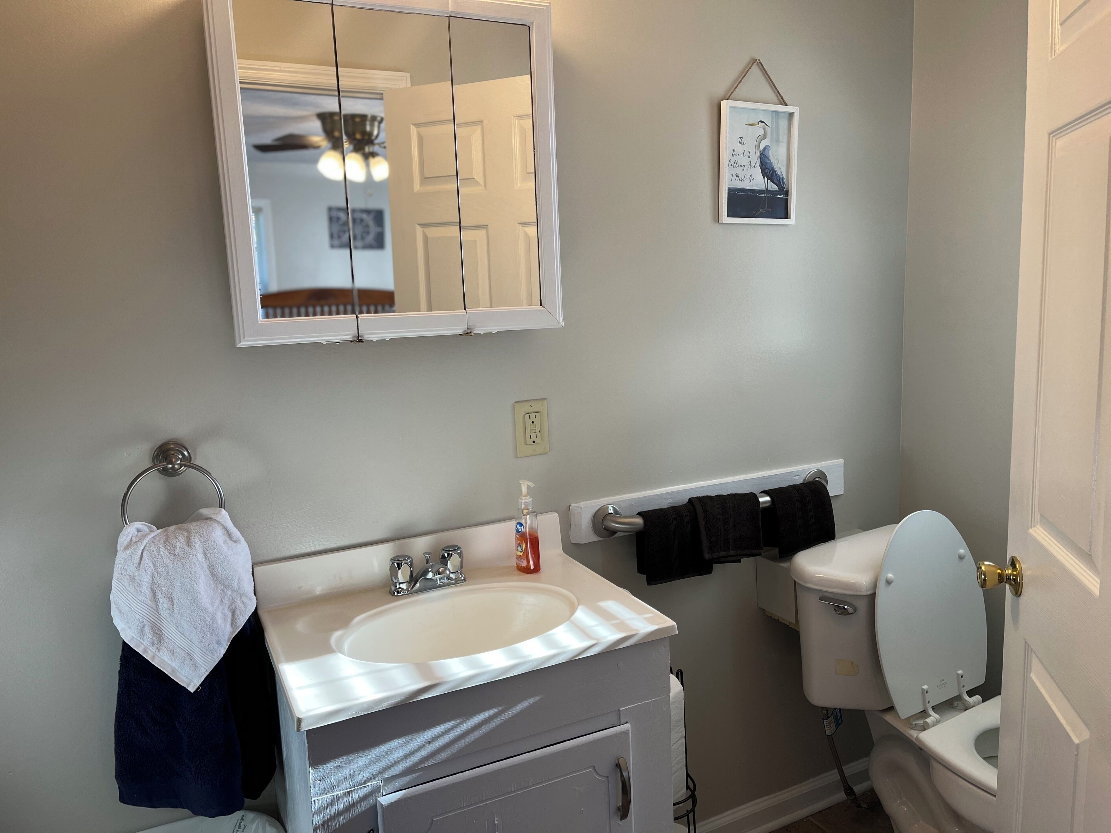 A bathroom with a white sink, a mirror, a toilet, and a towel rack.