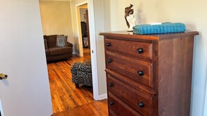 Une commode en bois avec des tiroirs et des poignées, une serviette bleue posée sur le dessus, et une figurine décorative.