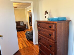 A wooden dresser with drawers and knobs, a blue towel on top, and a decorative item. - Inviting 4-Bedroom Americus Home Featuring Accessibility Enhancements (Americus)
