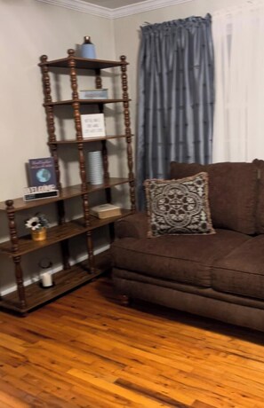 A wooden bookshelf, a brown sofa, and a patterned pillow.