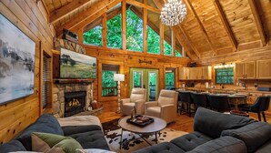 L’intérieur d’une cabane en rondins comprend une cheminée, un coin salon, un espace repas et une cuisine.