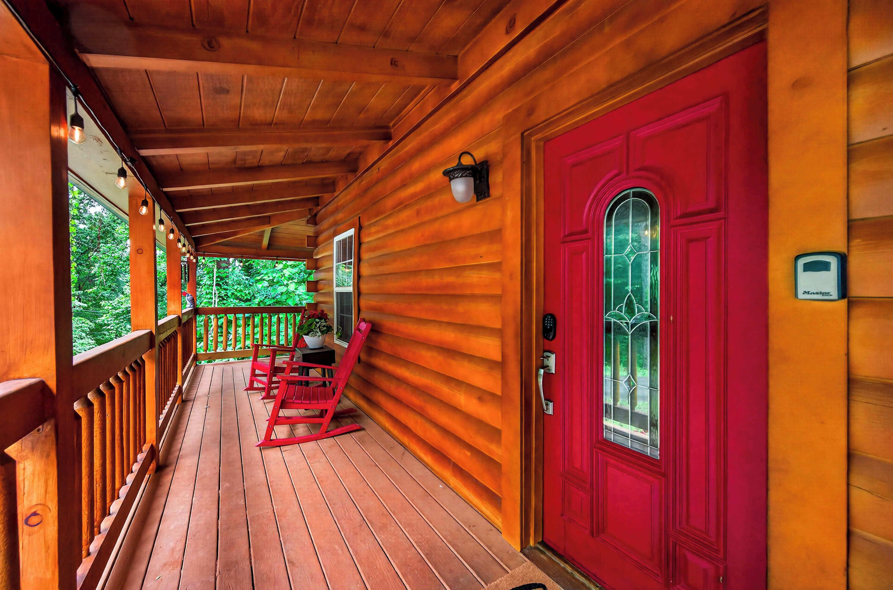 A wooden porch with a red door and a bench.