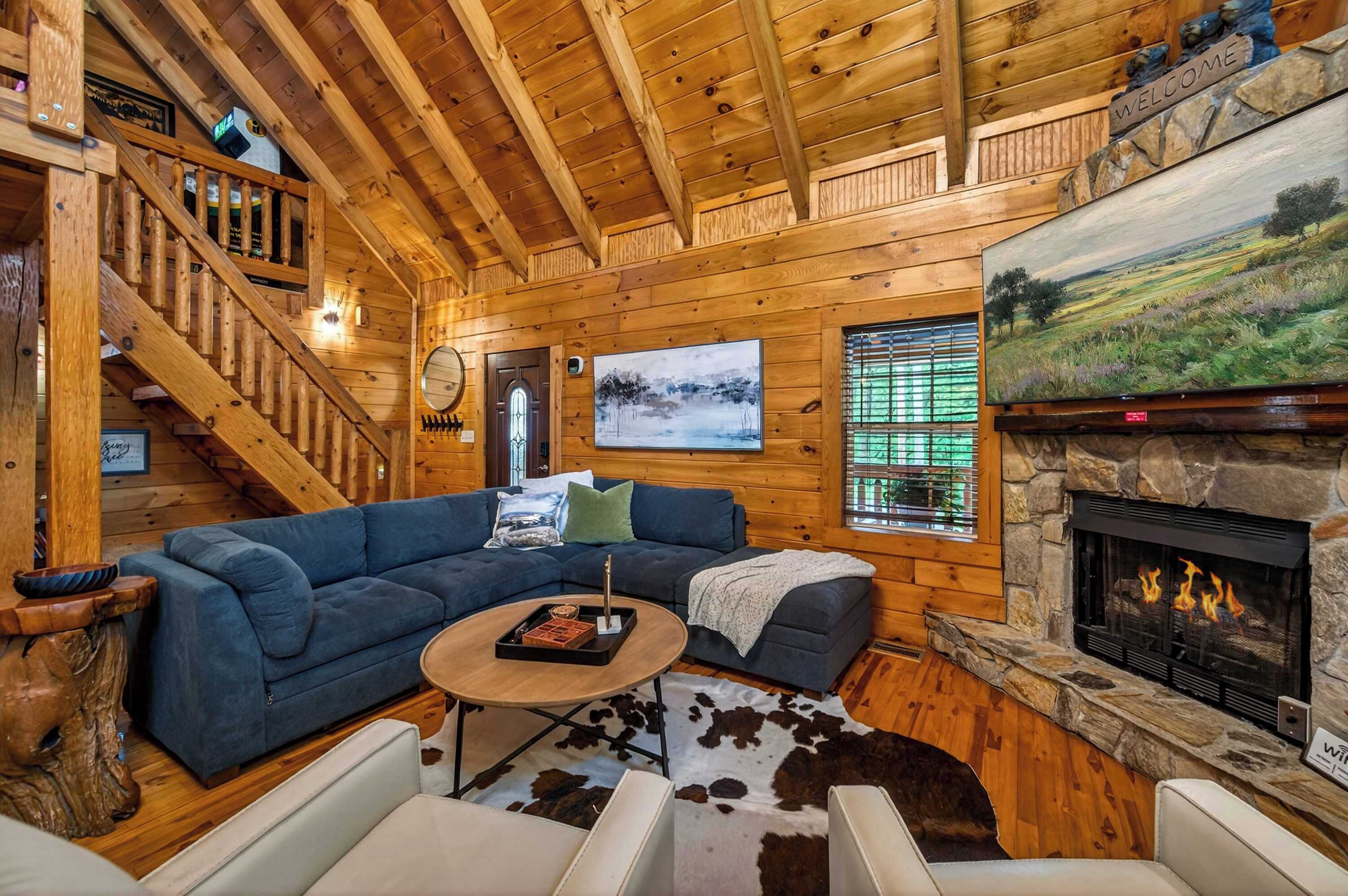 A wooden interior with a fireplace, a sofa, a coffee table, and a staircase.