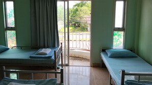 Quarto com duas camas de solteiro, janela com cortina e porta que dá para o exterior.