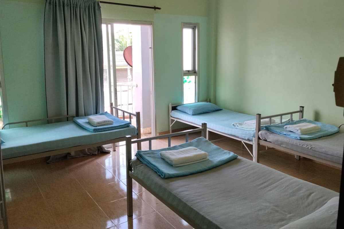 A room with four single beds, a window, and a door leading outside.