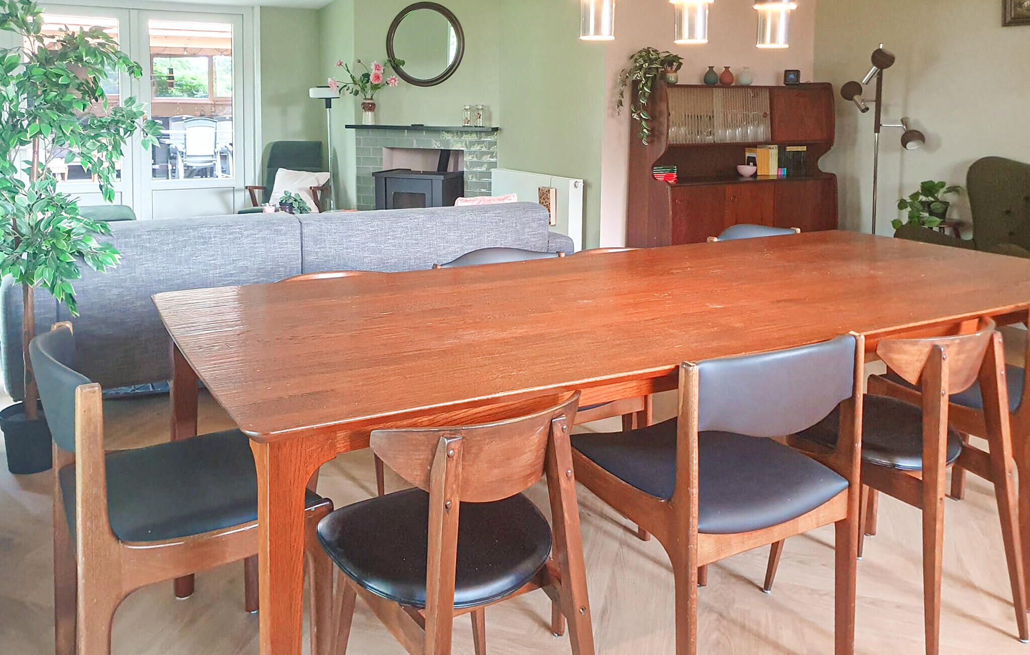 A dining area with a wooden table and chairs, a fireplace, and a green sofa.