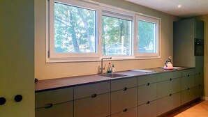 A kitchen with a window, sink, and cabinets.