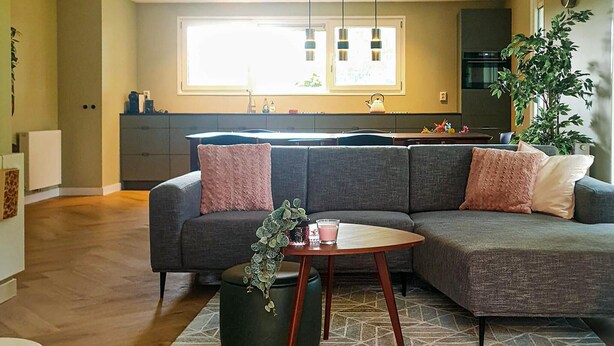 A modern living room with a grey sectional sofa, a small round table, and a potted plant.