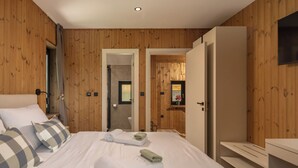Un dormitorio con cama, almohadas, un armario y un baño visible a través de una puerta abierta.