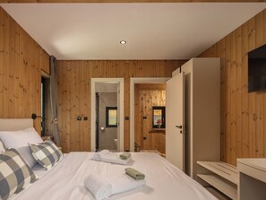 Ein Schlafzimmer mit einem Bett, Kissen, einem Kleiderschrank und einem durchgehenden Türrahmen sichtbaren Badezimmer.