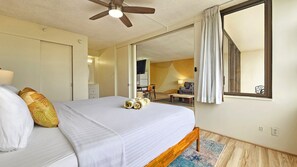 A bedroom with a bed, a ceiling fan, a window with curtains, and a view of a dining area. - Cozy 1-bedroom apartment in wonderful Honolulu with AC (Honolulu)