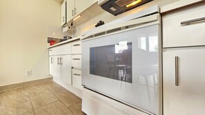 A kitchen with white cabinets, a stainless steel oven, and a tiled floor. - Cozy 1-bedroom apartment in wonderful Honolulu with AC (Honolulu)