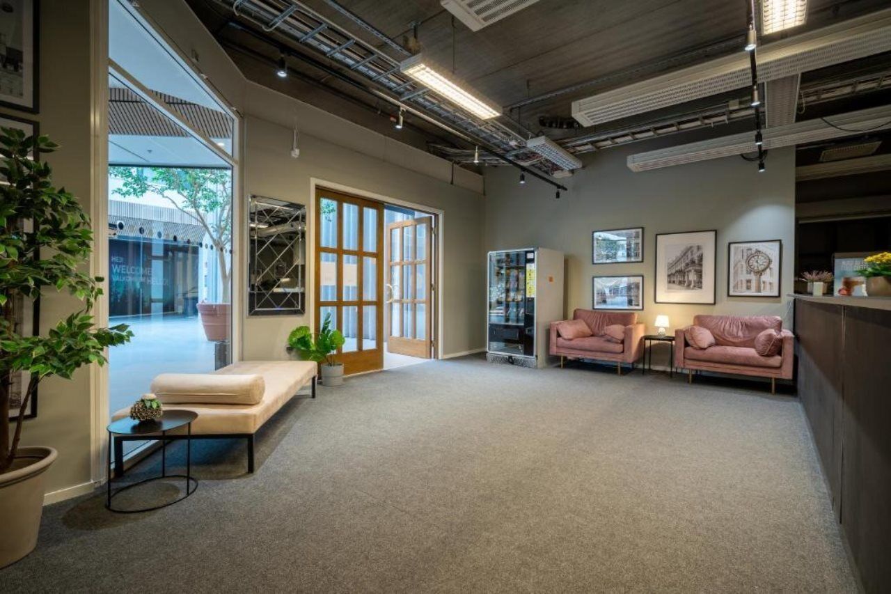 A spacious room with a sofa, two armchairs, a small table, and a bookshelf.