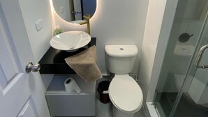 Un baño con lavamanos blanco, inodoro y cabina de ducha de cristal.