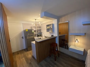 A compact kitchen with a built-in refrigerator, wooden accents, and a small dining area with stools.