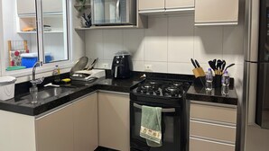 Ett modernt kök med spis, ugn, mikrovågsugn och kylskåp i rostfritt stål.