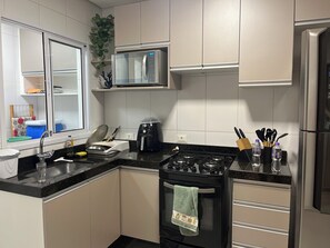 A modern kitchen with a stove, oven, microwave, and stainless steel refrigerator. - Wonderful apartment 50 meters from the beach. (Bertioga)