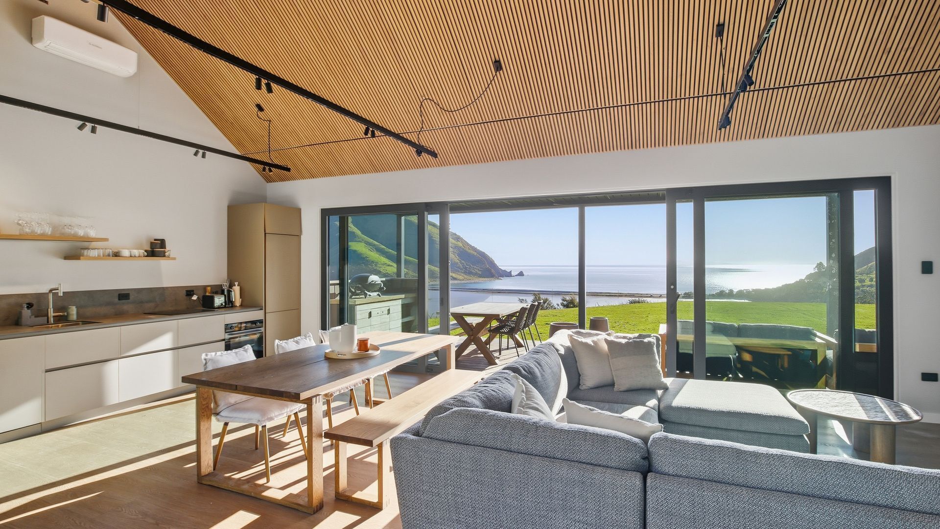 A modern kitchen with a large window, a dining area with a table and chairs, and a sofa.