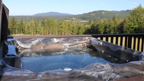 Een hottub op een terras met uitzicht op een bebost berglandschap.