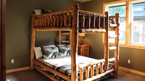 Een stapelbed met houten frame en een bedspread met dessin.