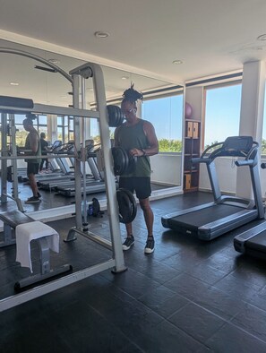 Ein Fitnessstudio mit Laufbändern, Gewichten und einer Bank.