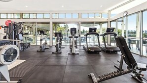 A gym with treadmills, weight machines, and a fan. - Peaceful Oasis, Prime Location - close to Pool, Gym, and Golf Courses (Hope Island)