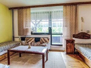 Quarto com sofá, cama, mesa e janela com cortinas.
