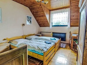 A room with a sloped wooden ceiling, a bed with a wooden frame, a window with a view, and a radiator. - Apartment Černý by Interhome (Rokytnice nad Jizerou)