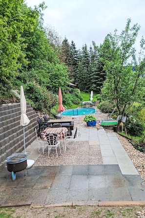 A backyard with a pool, outdoor seating, and a stone wall. - Apartment Černý by Interhome (Rokytnice nad Jizerou)