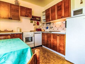 A kitchen with wooden cabinets, a stove, a microwave, and a refrigerator. - Apartment Černý by Interhome (Rokytnice nad Jizerou)