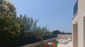 Eine Dachterrasse mit künstlichem Rasen, einem schwarzen Zaun und Gartenmöbeln.