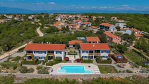A residential area with a swimming pool, houses with red roofs, and a clear sky. - Wabi Sabi Apt8 Pool & Sea View, Brzac, Croatia (Brzac)