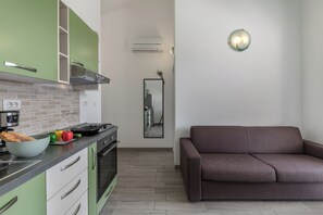 Eine moderne Küche mit grünen Schränken, einem braunen Sofa und einem Spiegel an der Wand.