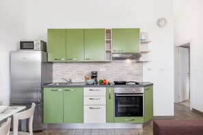 A compact kitchen with green cabinets, a stainless steel refrigerator, a microwave, and a built-in oven. - Wabi Sabi Apt8 Pool & Sea View, Brzac, Croatia (Brzac)