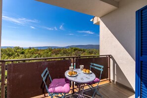 Ein Balkon mit Tisch, Stühlen und Blick auf die Landschaft.